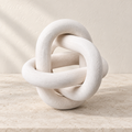 Knot white three-link wooden accent resting on a pale stone surface