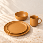 Ochre matte orange dinner plate, smaller plate, bowl and mug shown as a place setting