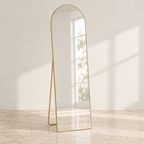 Linea arched full-length mirror with a gold-tone frame in a sunlit room