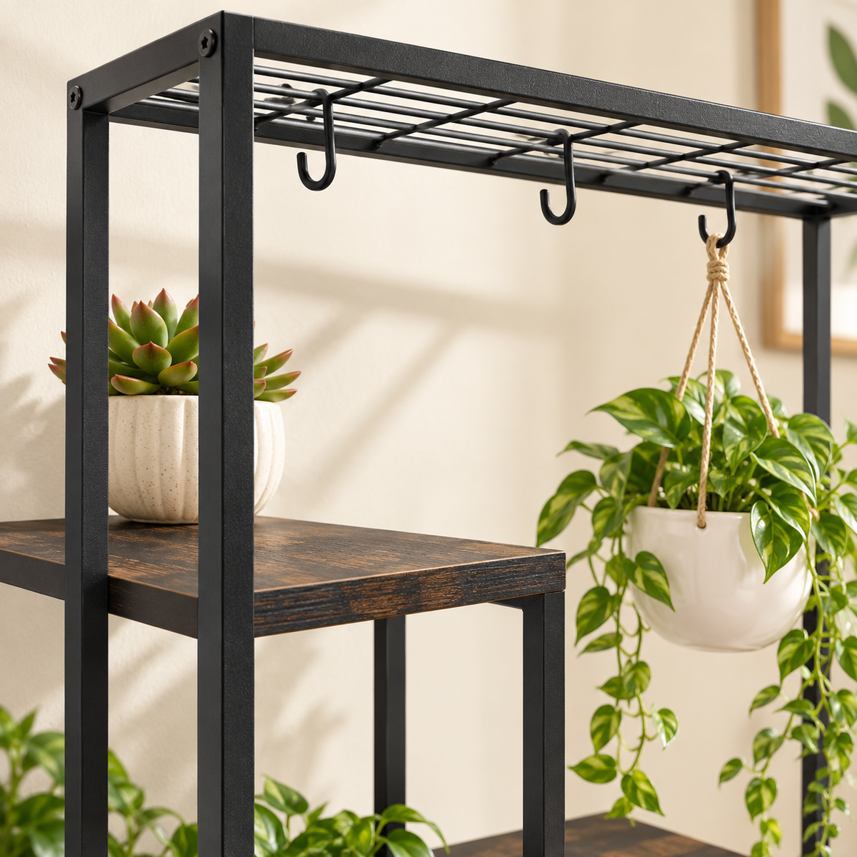 Close-up of the Aster plant stand black metal top rail, hanging hooks, and engineered wood shelf