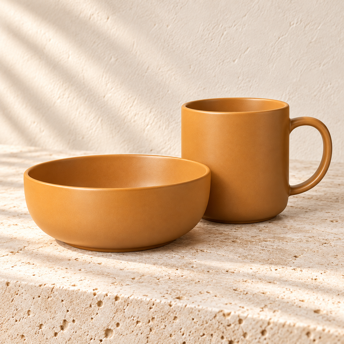 Ochre stoneware bowl and handled mug on a pale stone surface