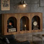 Arched wood console table styled with a record player, candle, and vintage clock in an industrial living room.