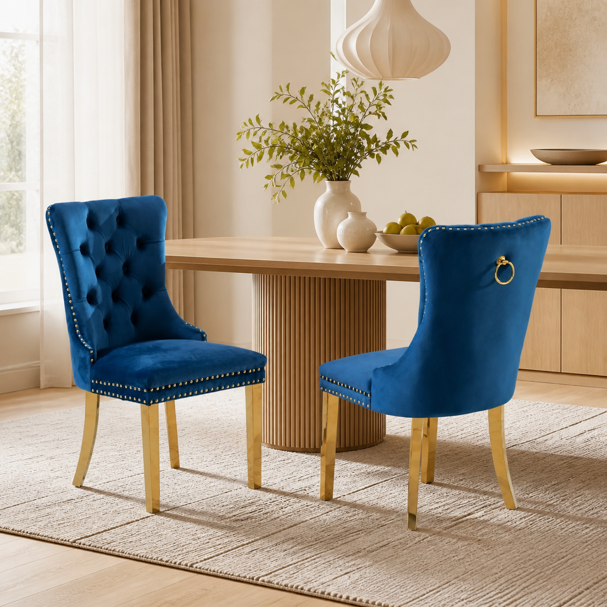 Two Elara blue velvet dining chairs with gold-tone legs in a warm modern dining room