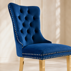Close-up of Elara blue velvet dining chair tufting, nailhead trim and gold-tone legs