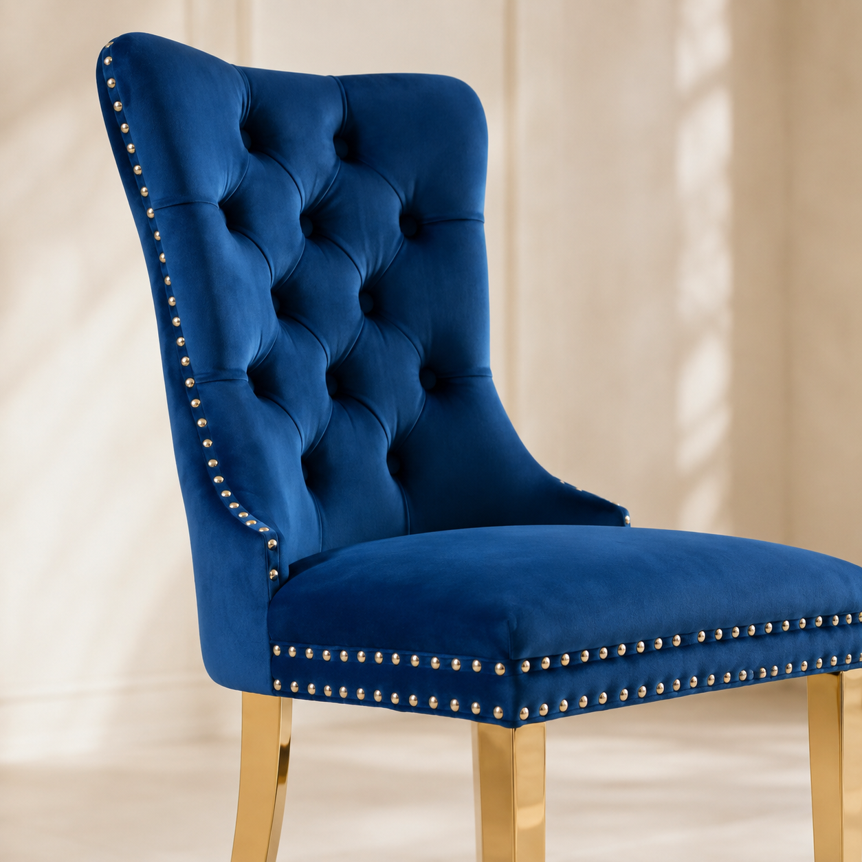 Close-up of Elara blue velvet dining chair tufting, nailhead trim and gold-tone legs