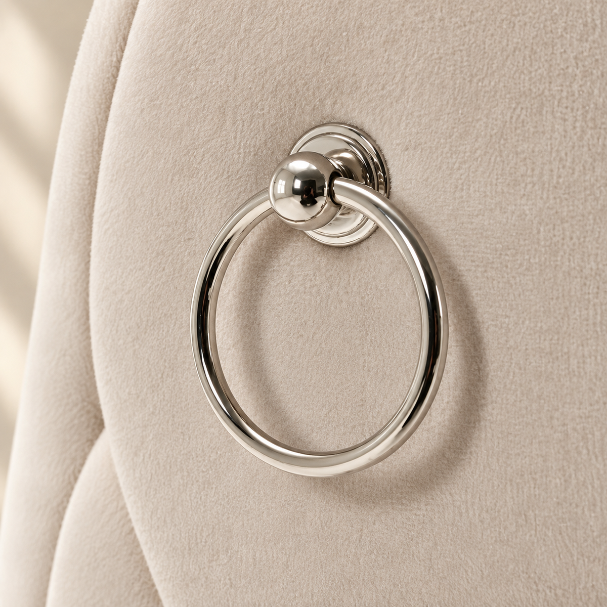 Polished chrome ring pull on the beige velvet back of an Elara dining chair
