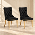 Two Elara black velvet dining chairs with gold-tone legs in a warm cream interior