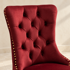 Close-up of burgundy velvet button tufting and gold nailhead trim