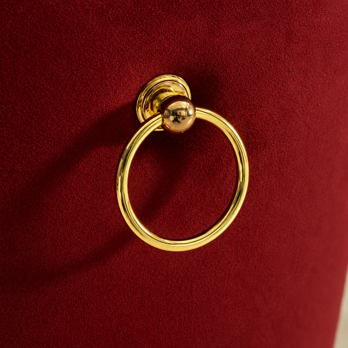 Polished gold ring pull on the burgundy velvet back of an Elara chair