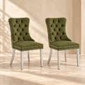 Two Elara olive green velvet dining chairs with silver chrome legs in a warm cream interior