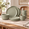 Sage green stoneware plates, bowls and mugs arranged on a dining table